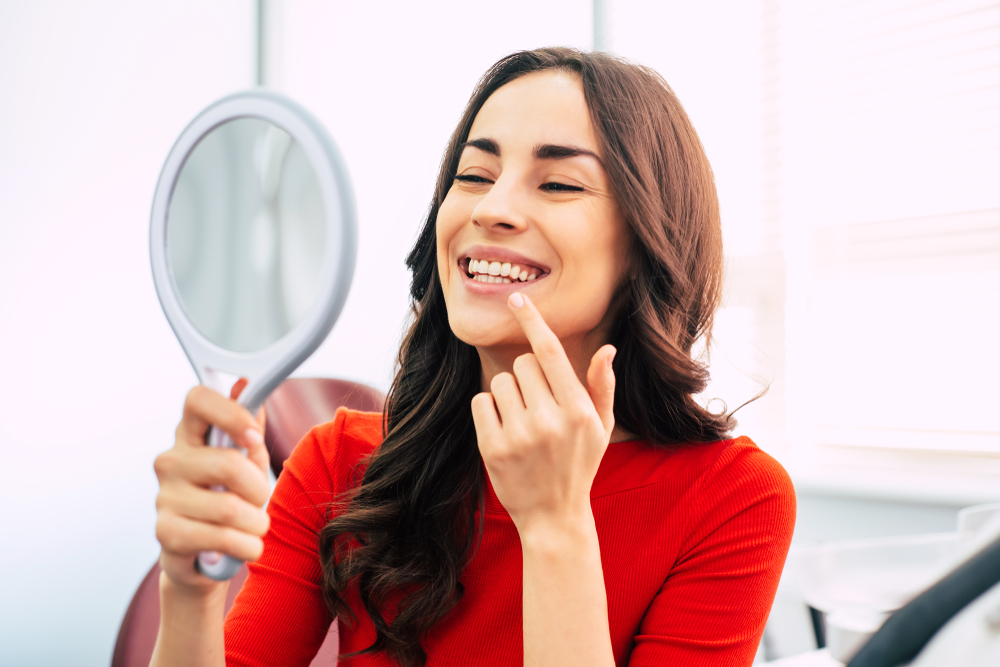 A woman in red checking her teeth - Cosmetic Dentist in Johns Creek