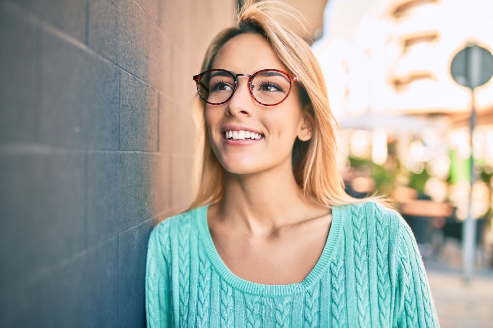 woman wearing glasses leaning on a wall