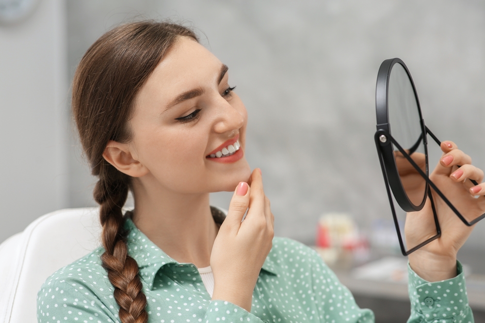 A braided woman checking her teeth - Cosmetic Dentist in Cumming GA