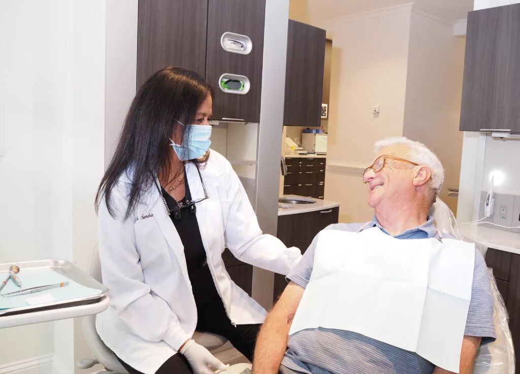 Dr. Sandra L. Vargas DMD, DDS of North Atlanta Family Dentistry is about to perform treatment on an elderly man - North Atlanta Family Dentistry Dr. Sandra L. Vargas DMD, DDS of North Atlanta Family Dentistry is about to perform treatment on an elderly man - North Atlanta Family Dentistry