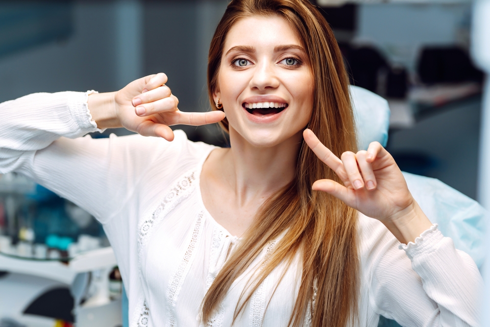 A woman pointing at her teeth - Cosmetic Dentist in Cumming GA
